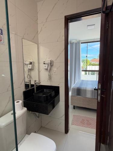a bathroom with a sink and a toilet and a bed at Flat do Lucca 02 - Piscina - 50m da Praia - Até 10 Pessoas in Tamandaré