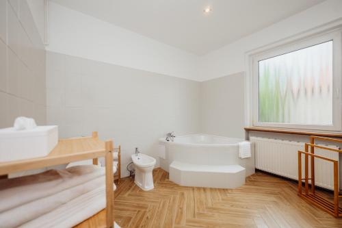 a bathroom with a tub and a toilet and a sink at Willa Berg Cieplice in Jelenia Góra