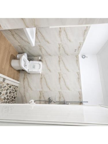 a white marble bathroom with a camera on the wall at Aparthotel Fitimi in Borsh