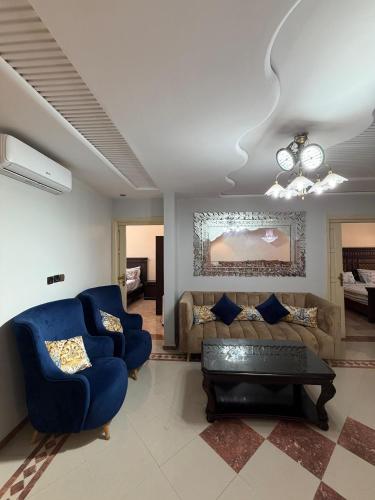 a living room with blue chairs and a couch at Villa le Palmier in Saïdia
