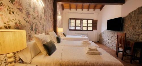 a bedroom with two beds and a tv on the wall at El Juacu in Llanes