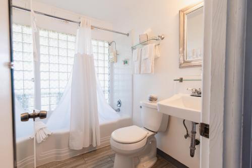a white bathroom with a toilet and a sink at Tillicum Beach Motel - Formerly Deane's Oceanfront Lodge in Yachats