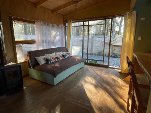 a living room with a couch in front of windows at Cabaña en Buchupureo in Tiuquilemu
