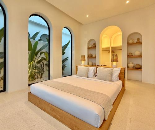 a bedroom with a large bed with large windows at The Young Villas - 1 Bedroom Villas, Bingin in Uluwatu