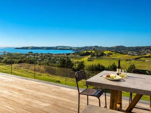a table and chairs on a deck with a view of the ocean at Overview - Stay Waiheke in Ostend