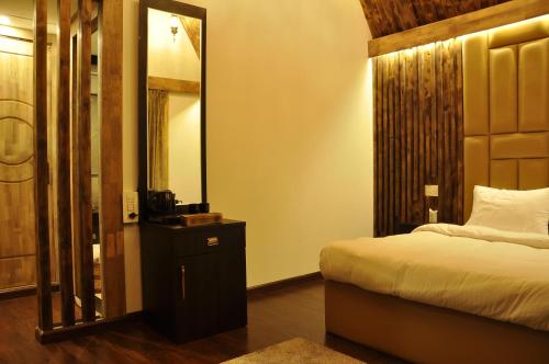 ein Schlafzimmer mit einem Bett und einem großen Spiegel in der Unterkunft CEDARS Resorts - Doodhpathri Kashmir in Rengazabal