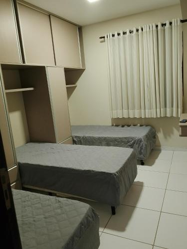 a room with two beds and a cabinet at Flat em Gravatá -Villa Monte Castelo - 2 quartos- Ao Lado da Área de Lazer e das piscinas in Gravatá
