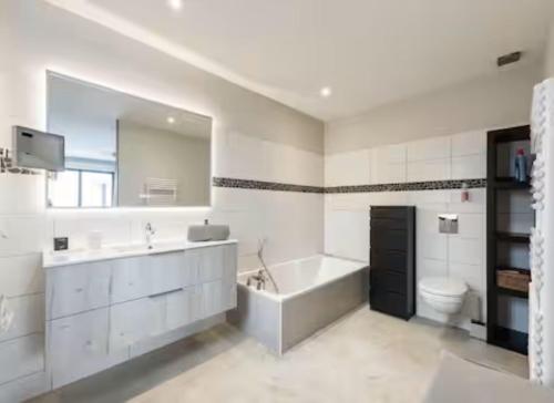a bathroom with a tub and a sink and a toilet at KeschtaLoft - Gîte classé 4 étoiles in Châtenois