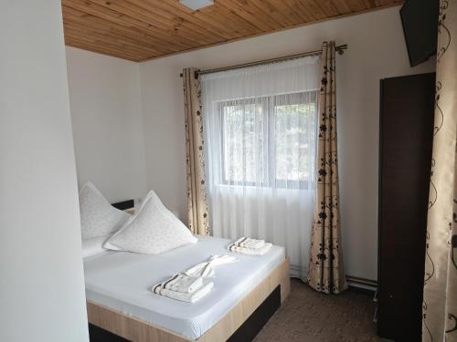 a bedroom with a bed with white sheets and a window at Serbeca in Broşteni