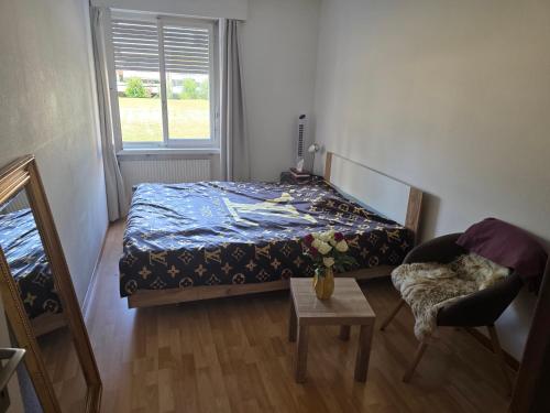 a bedroom with a bed and a chair and a table at Gemütliches Zimmer in ruhiger Umgebung in Privatwohnung in Lyss