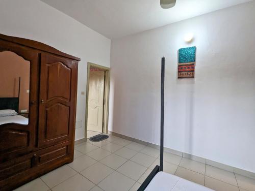 a room with a bed and a wooden cabinet at Petit Cocon de Ouidah - Chambre Cosy Climatisée - Plage a 10 min - Salon, Cuisine et balcon in Ouidah