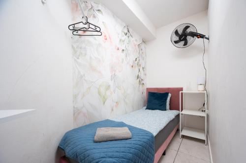 a small bedroom with a blue bed and a wall at S-HE Space - Budget Micro Rooms Kraków in Krakow