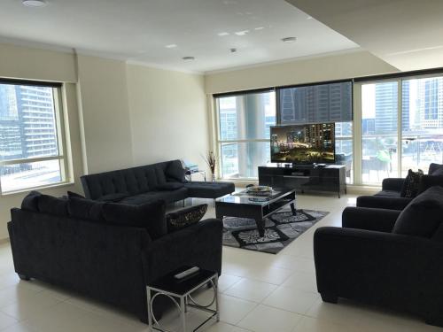 a living room with black furniture and large windows at My-Places Dubai Apartment suitable for large groups Al Sahab 1 in Dubai
