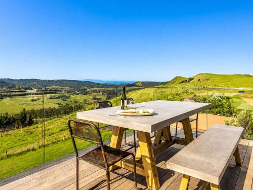 a table and chairs on a deck with a view at Overview - Stay Waiheke in Ostend