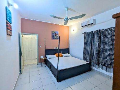 a bedroom with a bed and a ceiling fan at Petit Cocon de Ouidah - Chambre Cosy Climatisée - Plage a 10 min - Salon, Cuisine et balcon in Ouidah