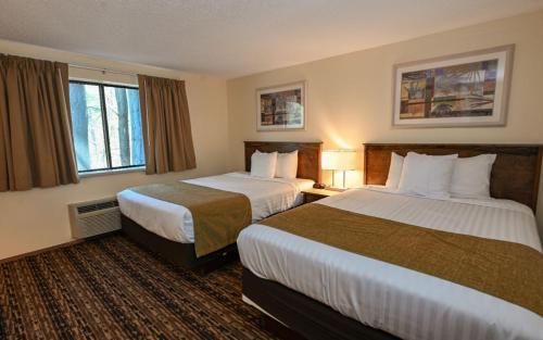 a hotel room with two beds and two windows at Sunset Bay Resort & Suites in Wisconsin Dells