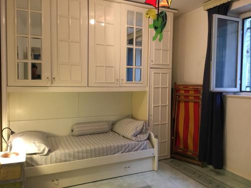 a room with a bed with white cabinets and a window at La Casa di Zoe in Uscio