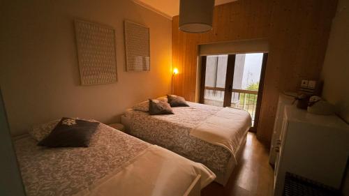 two beds in a room with a window at Casa da Serra - T1 - Penhas da Saúde in Penhas da Saúde