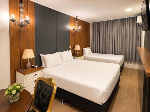 a hotel room with a bed and a desk and a table at Eleganz Suítes Exclusive Centro in Gramado