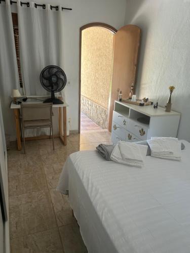 a bedroom with a bed and a desk and a window at Suite LUAR in Saquarema