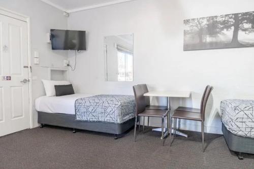 a bedroom with a bed and a table and chairs at Nicholas Royal Motel - Hay CBD in Hay