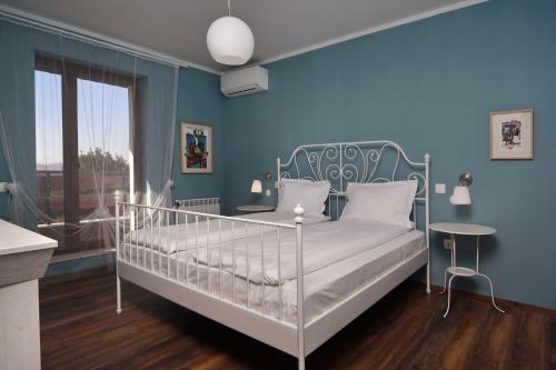 1 dormitorio con 1 cama blanca en una pared azul en Esterra Vini Guest House, en Perushtitsa
