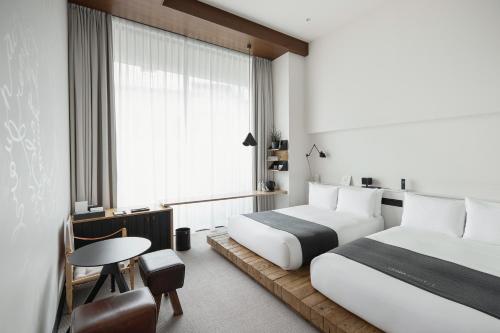 a hotel room with two beds and a table and a window at TRUNK(HOTEL)CAT STREET in Tokyo