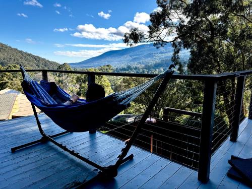 a person sleeping in a hammock on a deck at Sunset View House - Rustic Outdoor Bathhouse, Walk to Town in Warburton