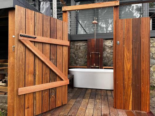 a bathroom with a wooden door and a bath tub at Sunset View House - Rustic Outdoor Bathhouse, Walk to Town in Warburton