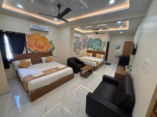 a bedroom with two beds and a couch and a television at Jay & Jas Hotel in Tirupati
