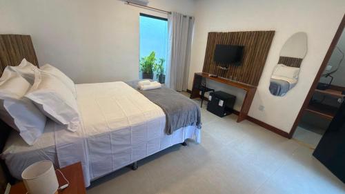 a bedroom with a bed and a television in it at Pousada Ville Solare Garden in Santo Amaro