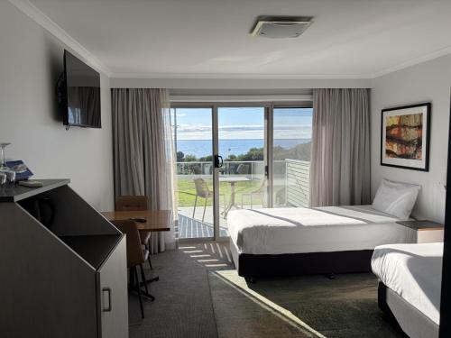 a hotel room with a bed and a balcony at Beachfront Bicheno in Bicheno