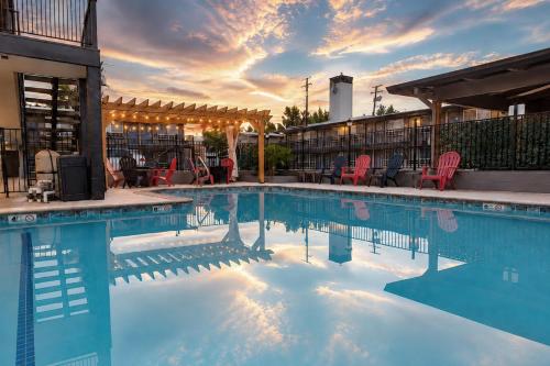 a swimming pool with red chairs and a sunset at Thunderbird Lodge in Redding