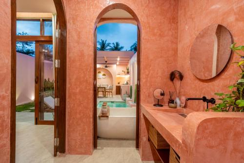 an orange bathroom with a tub and a sink at Villa Solea in Gili Trawangan