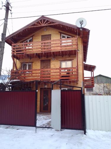 una casa de madera con puertas rojas en la nieve en U Karoliny en Yaremcha