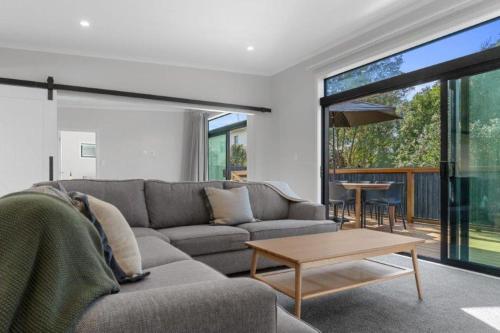 a living room with a couch and a table at Recline on Leo in Waihi Beach