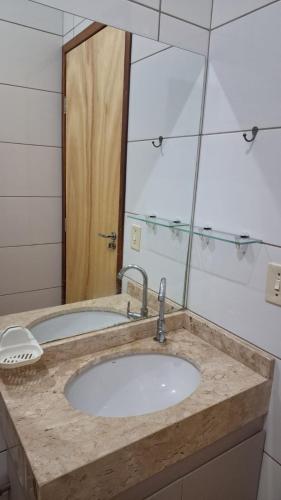 a bathroom with a sink and a large mirror at Suíte privativa com acesso à rua in Dourados