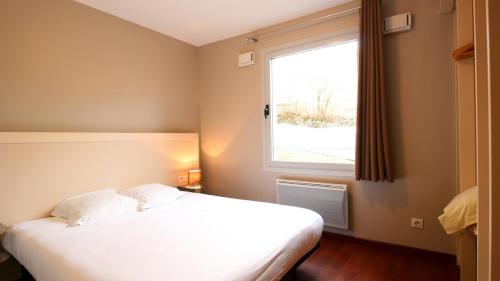 1 dormitorio con cama blanca y ventana en Aux Balcons du Sancy, en Picherande