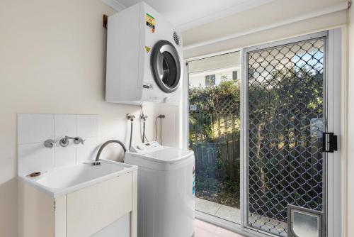 a bathroom with a sink and a washing machine at Skippers Place in Noosaville