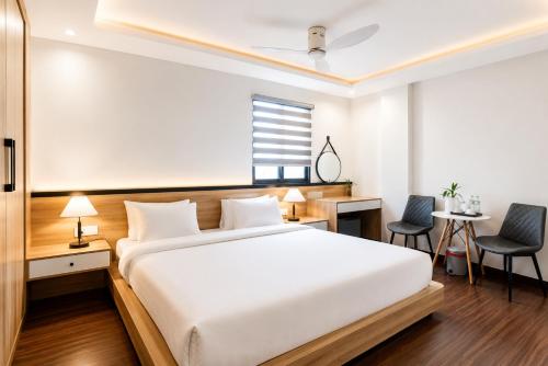a bedroom with a white bed and a desk and chairs at Awesome Hanoi Hostel & Travel in Hanoi