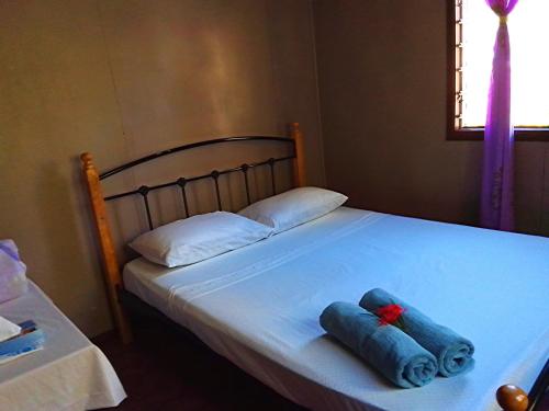 a bed with two blue towels sitting on it at Nukuwasiga homestay in Soso