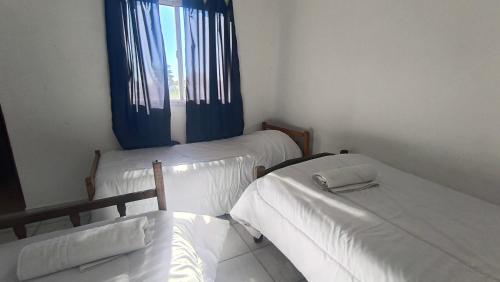 a room with two beds and a window with blue curtains at Dpto GAMA a cuadras del corso in Gualeguay