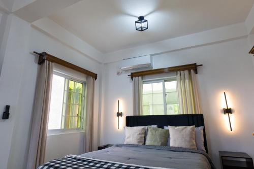 a bedroom with a bed and two windows at Green Valley Luxe Apartments in Kingstown