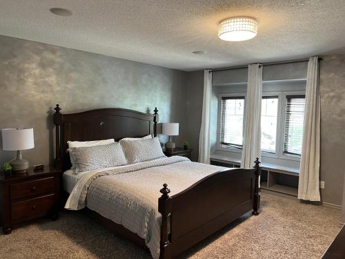 a bedroom with a large bed and two windows at Cozy Kitchener-Waterloo Home in Kitchener