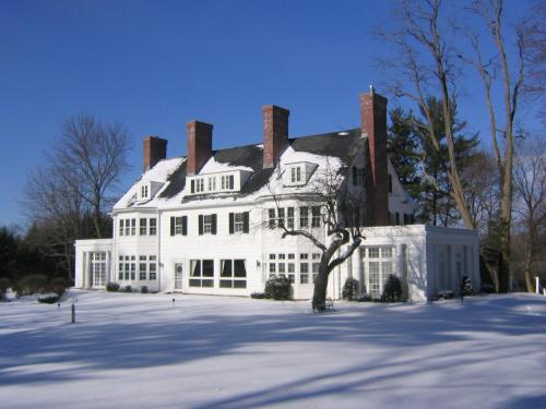 a large white house with snow on the ground at Four Chimneys Inn in Bennington