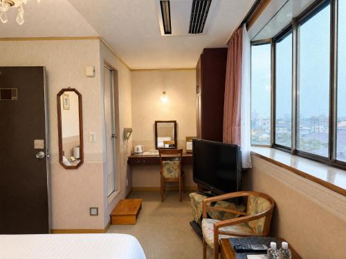 a room with a bed and a desk and a television at 和洲館ホテル in Gyōda