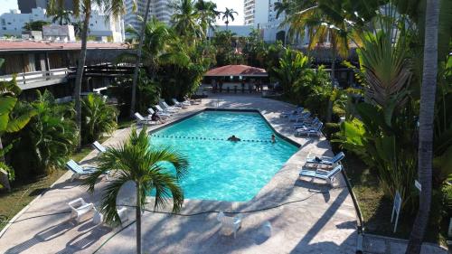 an overhead view of a swimming pool with chairs and palm trees at Hotel Bali-Hai Acapulco in Acapulco