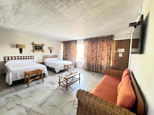 a hotel room with two beds and a couch at Hotel Bali-Hai Acapulco in Acapulco