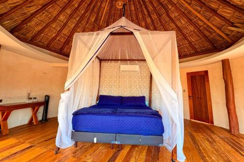 a bed with a mosquito net in a room at Cabanas Jaalkab in Chelem