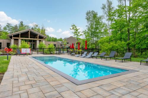 a swimming pool with chairs and a playground at Tremblant Prestige - Verbier 4-202 in Mont-Tremblant